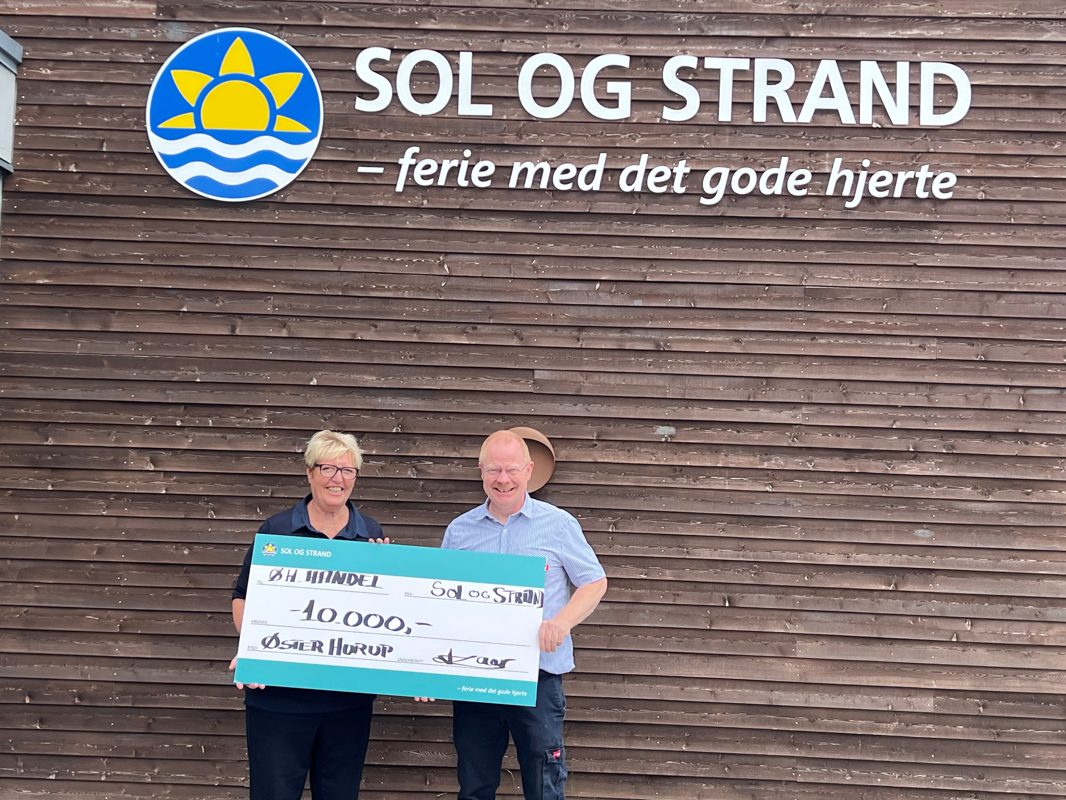 To personer fra sol og strand giver lokal håndsrækning på 10 tusinde kroner til Øster Hurup Handel